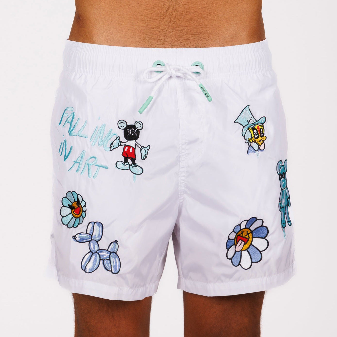 White swim shorts front view with illustrated graphic and “Falling in art” text