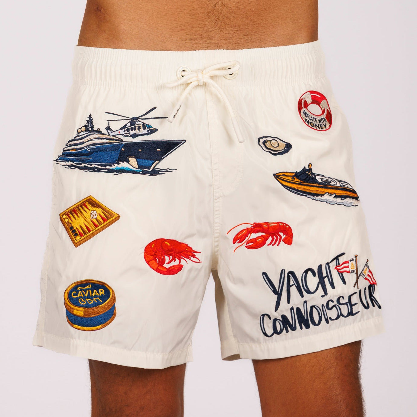Off-white swim shorts front view with illustrated graphic and “Yacht connoisseur” text