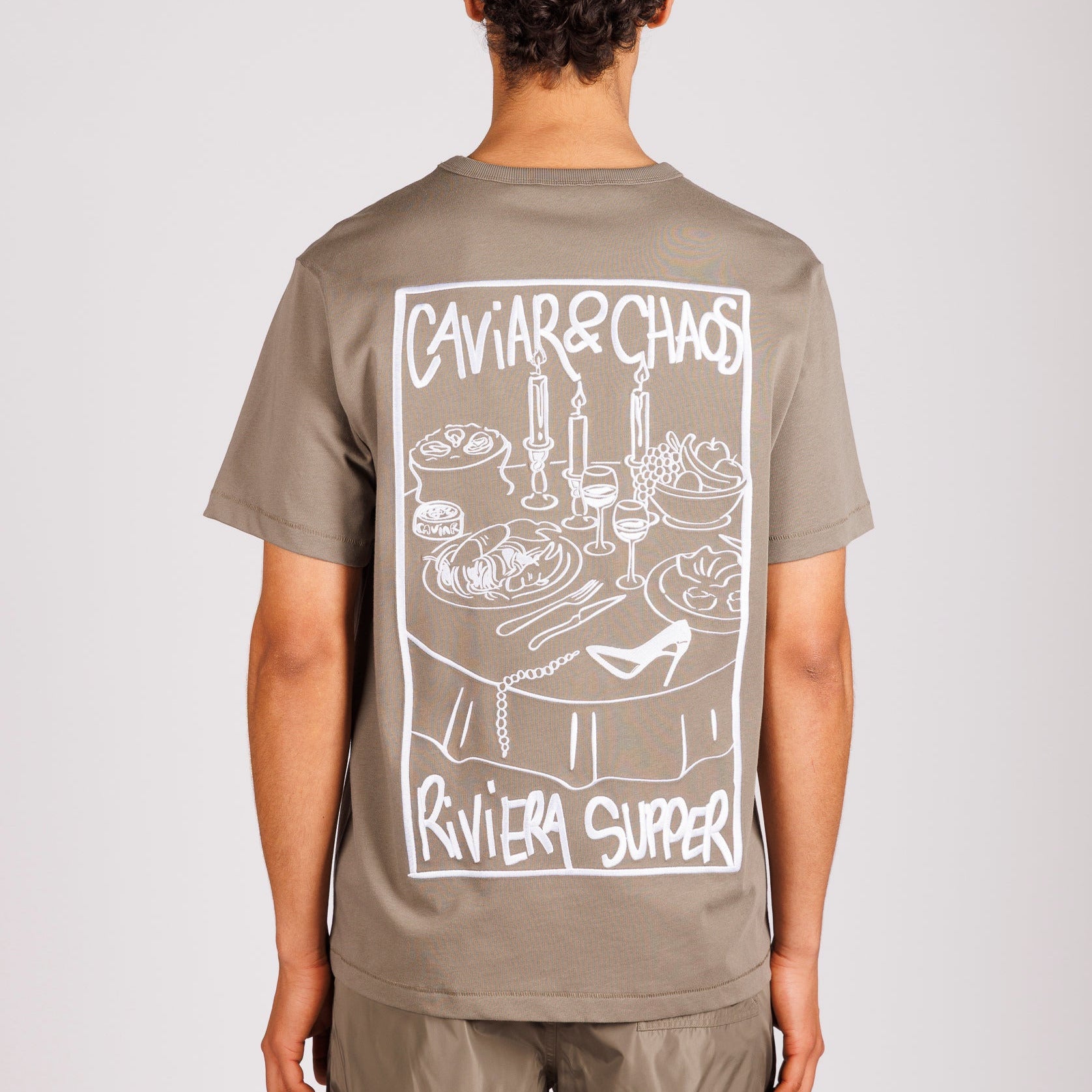 Military green T-shirt back view with illustrated graphic and “Caviar&Chaos Riviera Supper” text