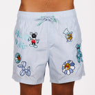 Light blue swim shorts front view with illustrated graphic and “Falling in art” text
