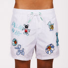 White swim shorts front view with illustrated graphic and “Falling in art” text