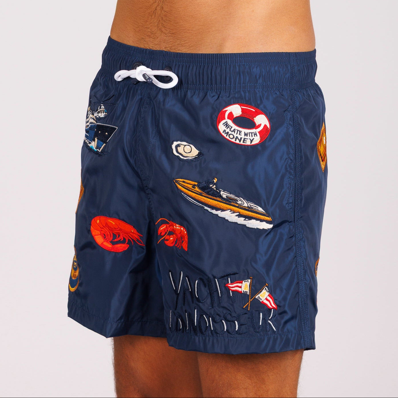 Navy blue swim shorts side view with illustrated graphic and “Yacht connoisseur” text